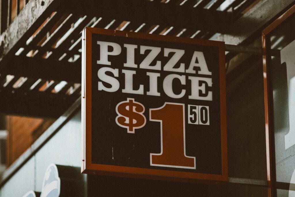 pizza pricing psychology: black billboard displaying price of a slice of pizza