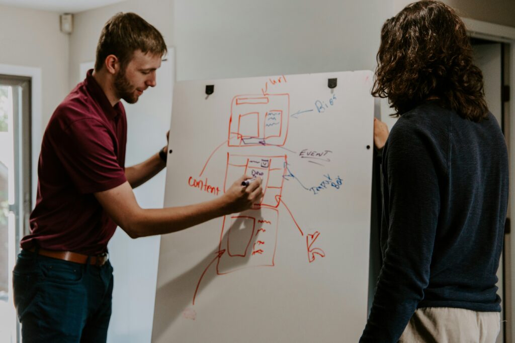 a man and a woman near a whiteboard drawing up a strategy